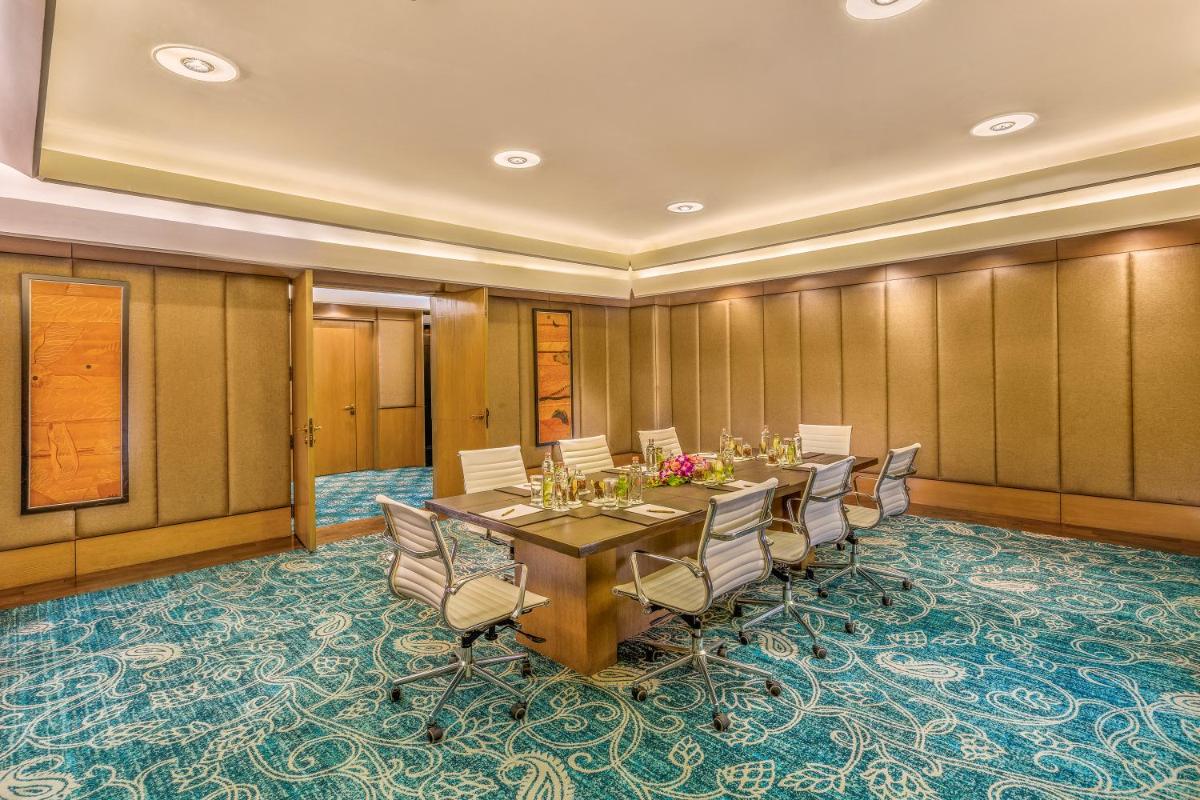 a conference room with a long table and chairs at The Leela Ambience Convention Hotel Delhi in New Delhi
