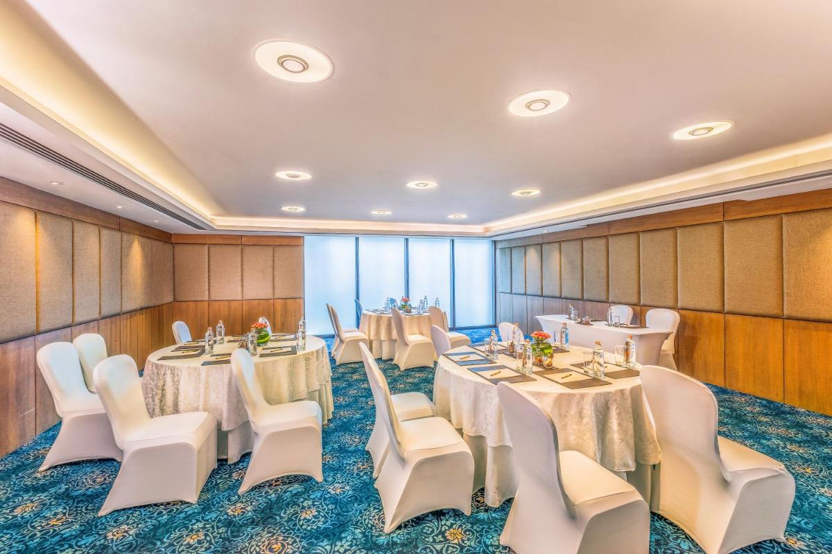 a conference room with tables and white chairs at The Leela Ambience Convention Hotel Delhi in New Delhi