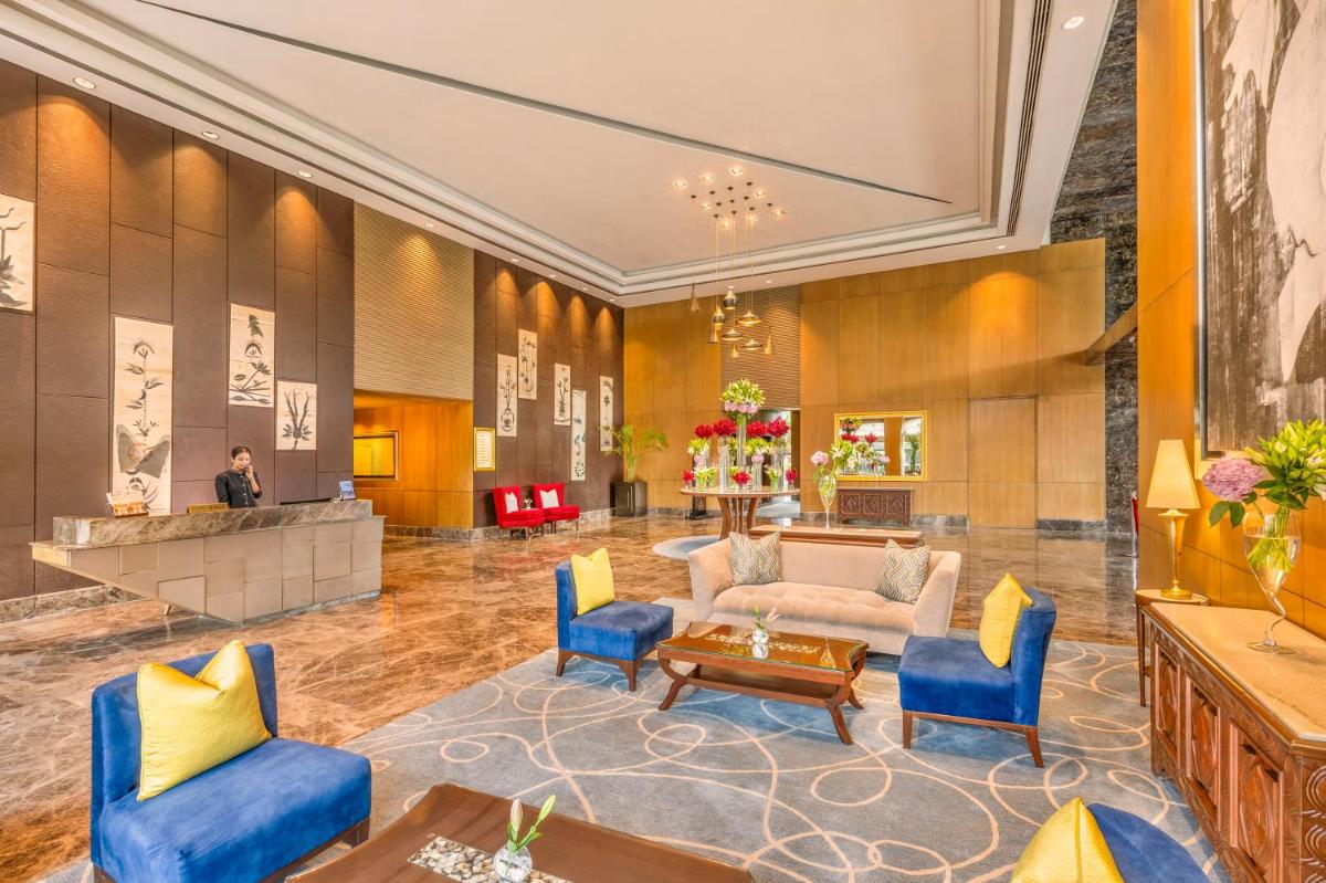 a lobby with blue chairs and a couch at The Leela Ambience Convention Hotel Delhi in New Delhi