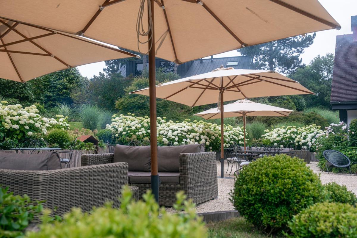 un groupe de parasols, de tables et de chaises dans l'établissement Les Pins de César - La campagne d'Etretat, à Saint-Jouin-Bruneval