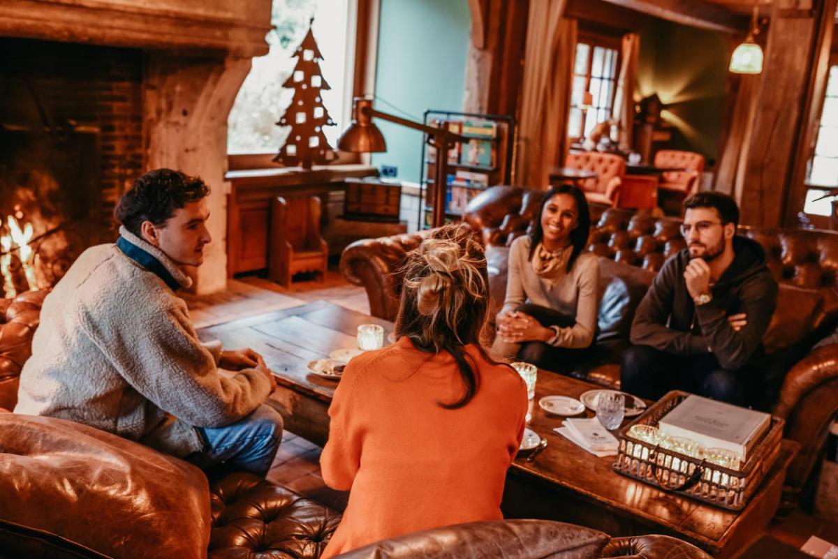 un groupe de personnes assises autour d'une table dans un salon dans l'établissement Les Pins de César - La campagne d'Etretat, à Saint-Jouin-Bruneval