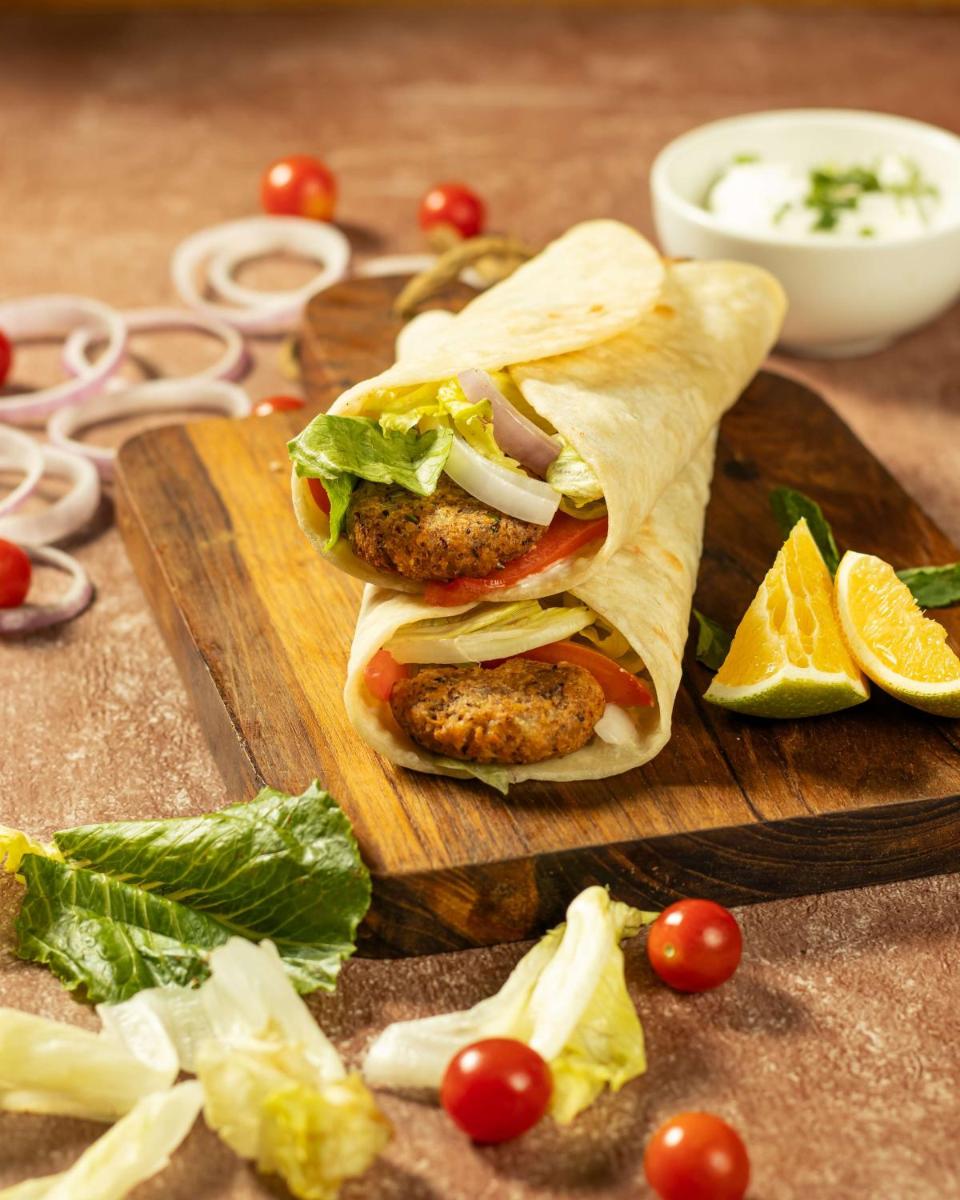 a sandwich on a cutting board with lettuce and tomatoes at Radisson Blu Hotel Ahmedabad in Ahmedabad