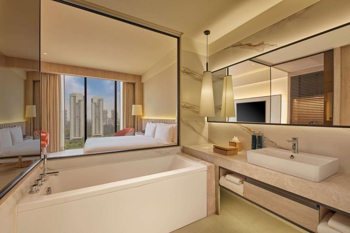 a bathroom with a tub and a large mirror at Hilton Gurugram Baani City Centre in Gurgaon