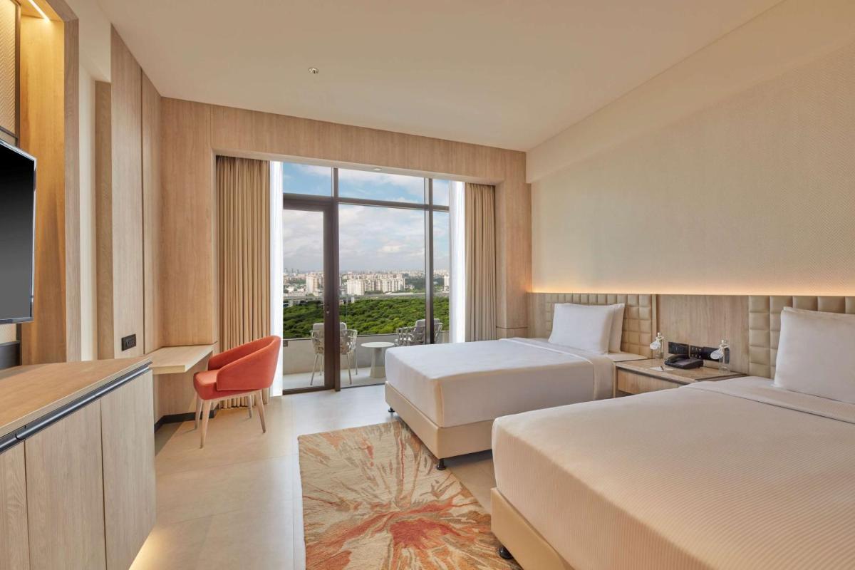 a hotel room with two beds and a large window at Hilton Gurugram Baani City Centre in Gurgaon