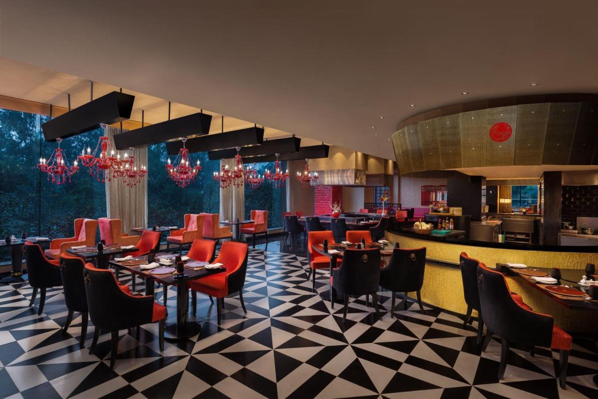 a restaurant with red chairs and tables and a bar at Sheraton New Delhi Hotel in New Delhi a restaurant with red chairs and tables and a bar at Sheraton New Delhi Hotel in New Delhi