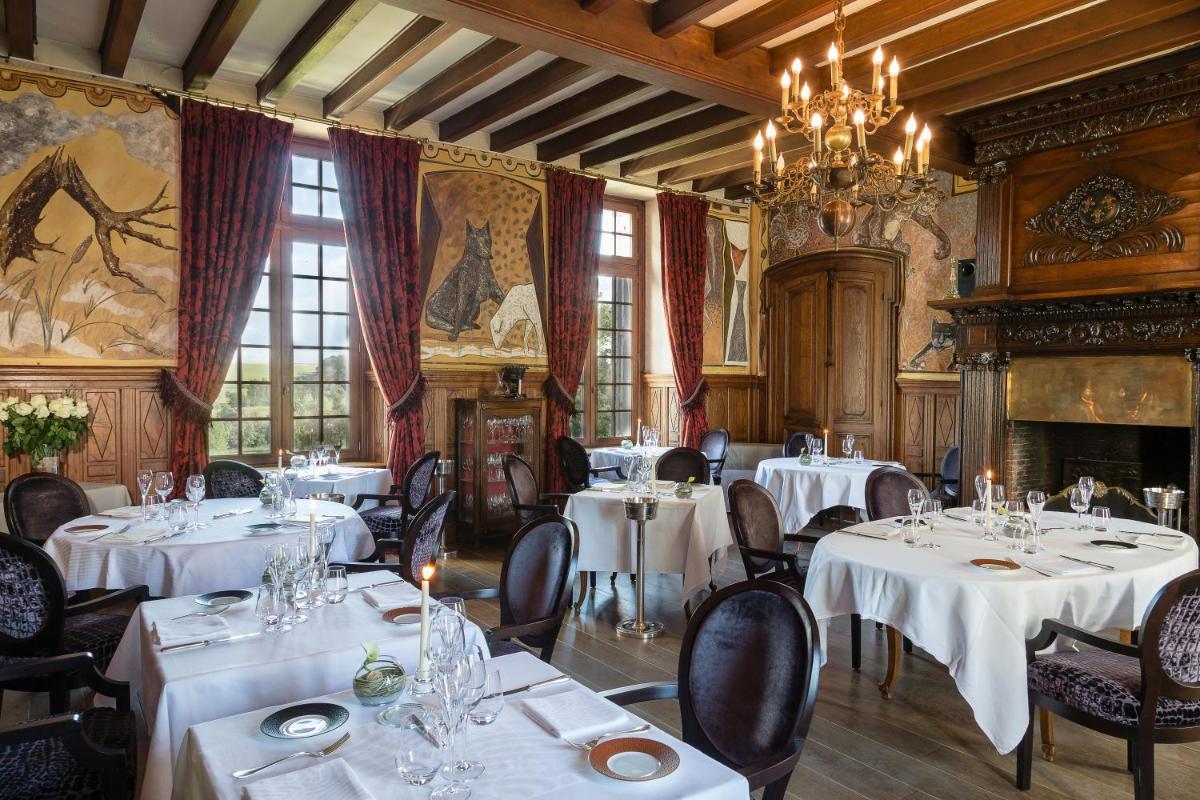 un restaurant avec des tables et des chaises blanches et un lustre dans l'établissement Chateau De Fere, à Fère-en-Tardenois