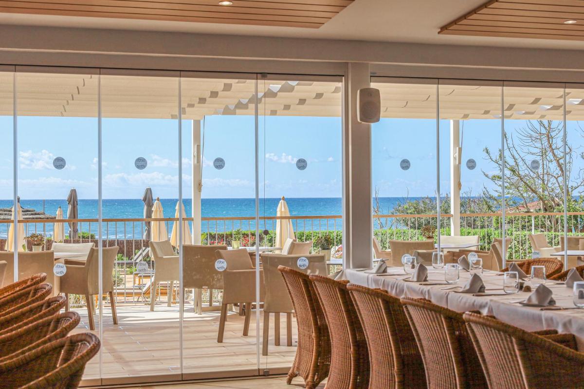 Un restaurante con mesas y sillas y vista al mar. en Seth Santo Tomás, en Santo Tomás
