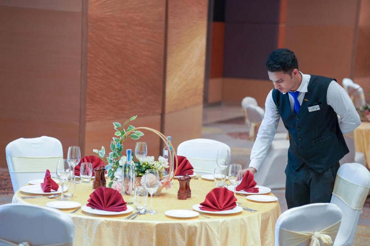 a man is standing over a table with red napkins at Radisson Blu Hotel Amritsar in Amritsar
