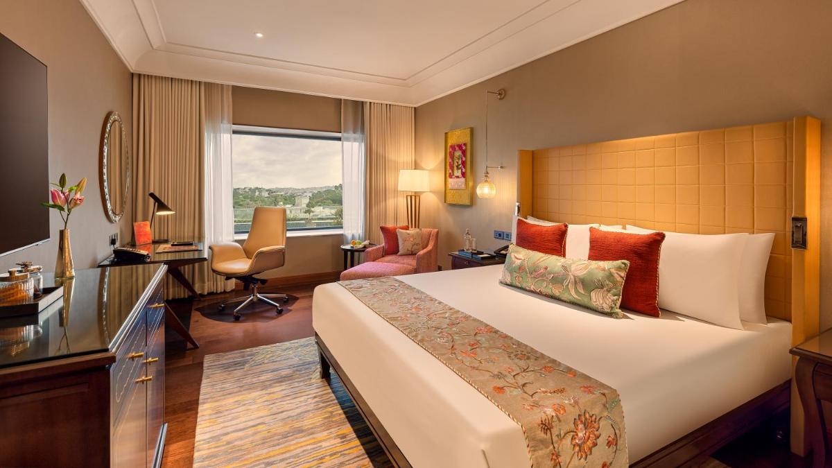 a hotel room with a large bed and a desk at The Leela Hyderabad Banjara Hills in Hyderabad a hotel room with a large bed and a desk at The Leela Hyderabad Banjara Hills in Hyderabad