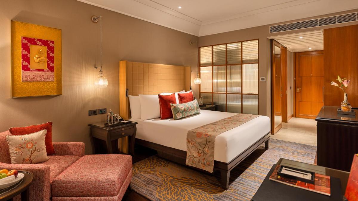 a hotel room with a bed and a chair at The Leela Hyderabad Banjara Hills in Hyderabad a hotel room with a bed and a chair at The Leela Hyderabad Banjara Hills in Hyderabad