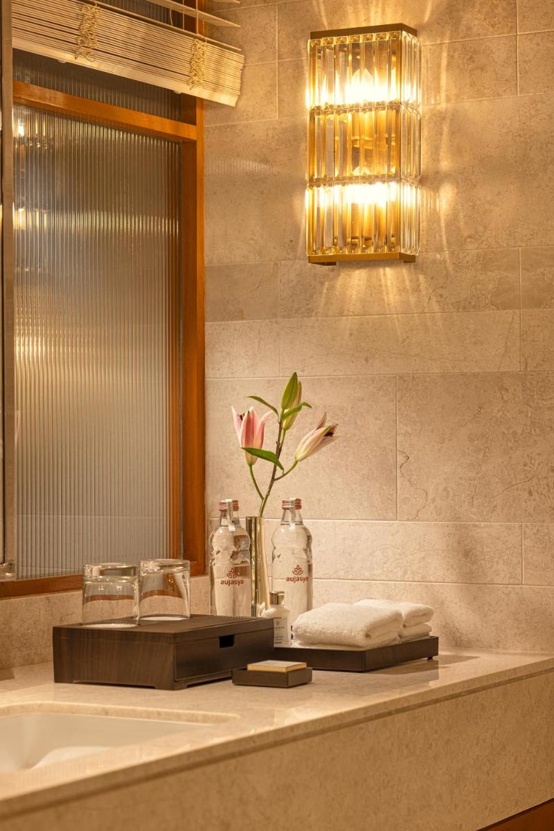 a bathroom with a sink and a vase with a flower at The Leela Hyderabad Banjara Hills in Hyderabad