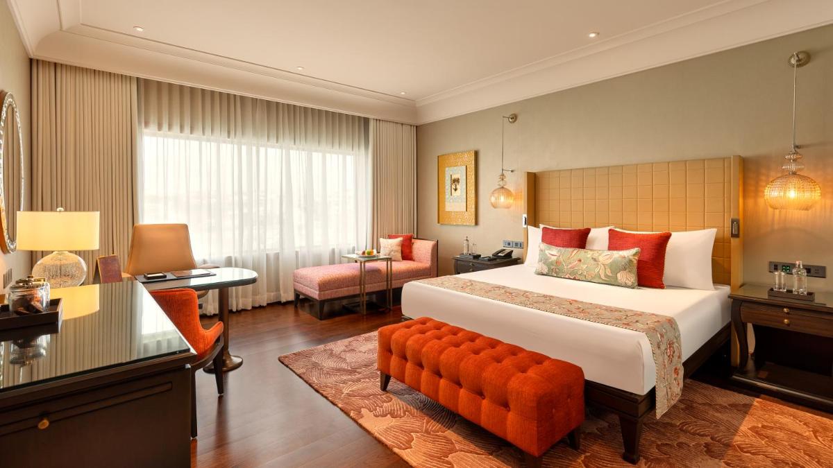 a hotel room with a large bed and a desk at The Leela Hyderabad Banjara Hills in Hyderabad