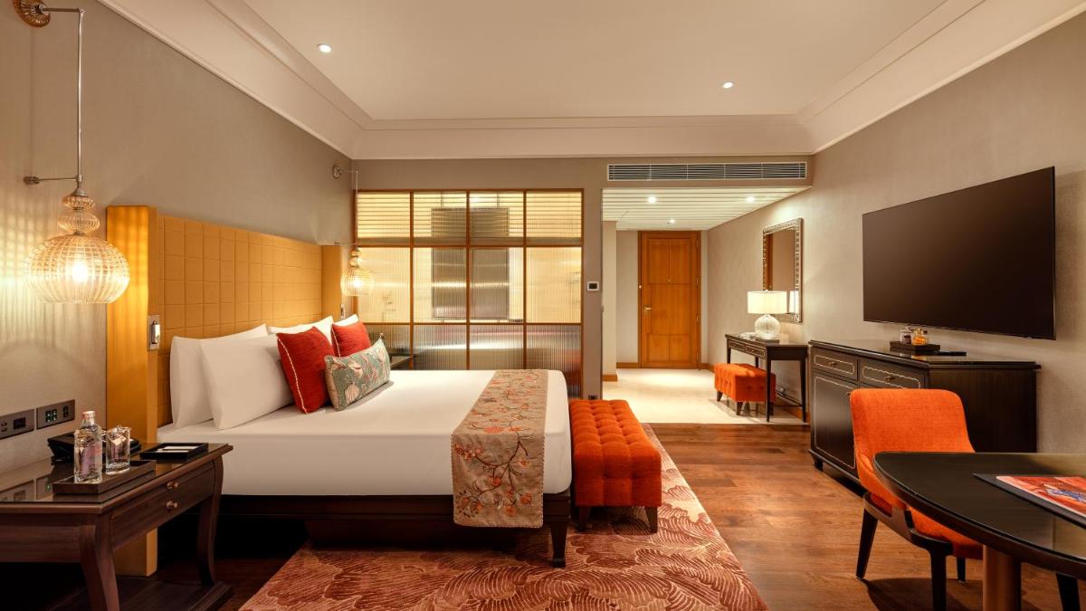 a hotel room with a bed and a flat screen tv at The Leela Hyderabad Banjara Hills in Hyderabad