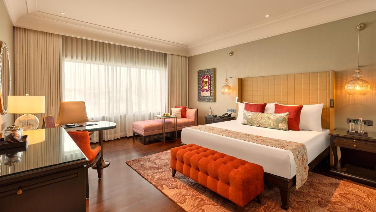 a hotel room with a large bed and a desk at The Leela Hyderabad Banjara Hills in Hyderabad