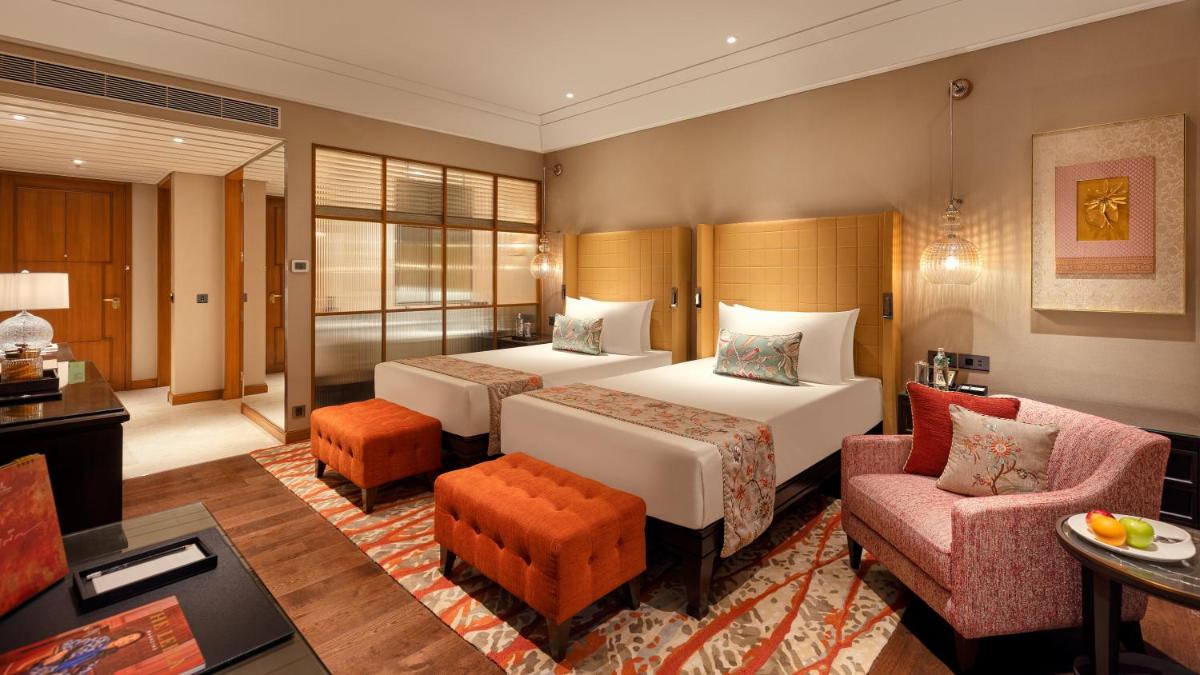 a hotel room with two beds and a living room at The Leela Hyderabad Banjara Hills in Hyderabad