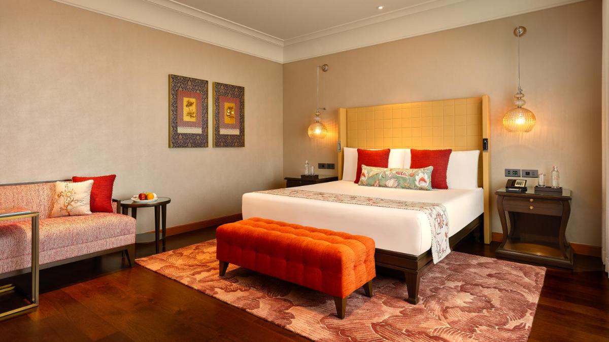 a bedroom with a large bed and a chair at The Leela Hyderabad Banjara Hills in Hyderabad