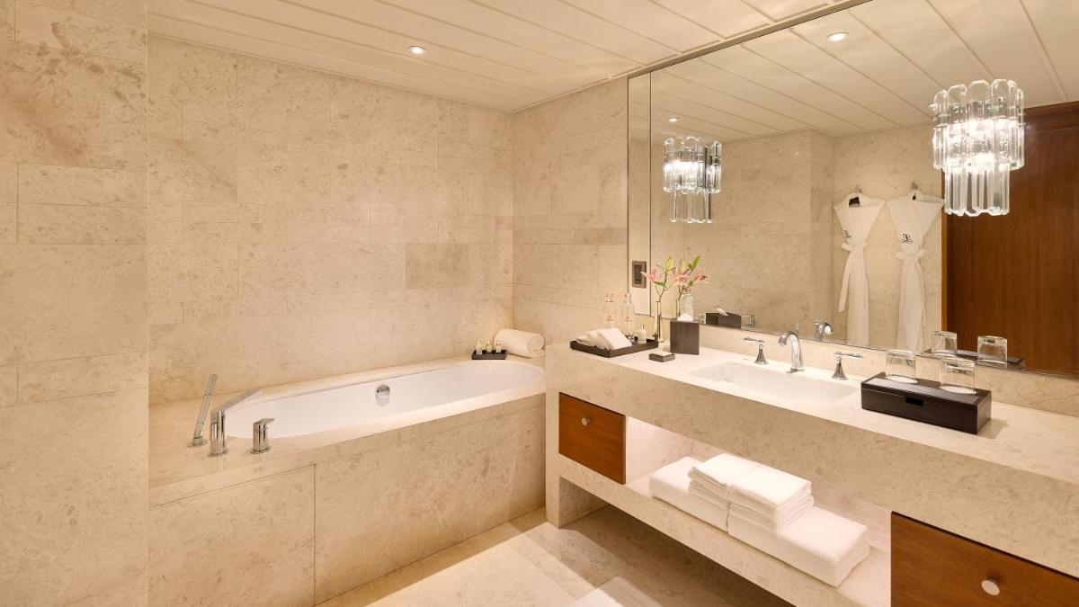 a bathroom with a tub and a large mirror at The Leela Hyderabad Banjara Hills in Hyderabad