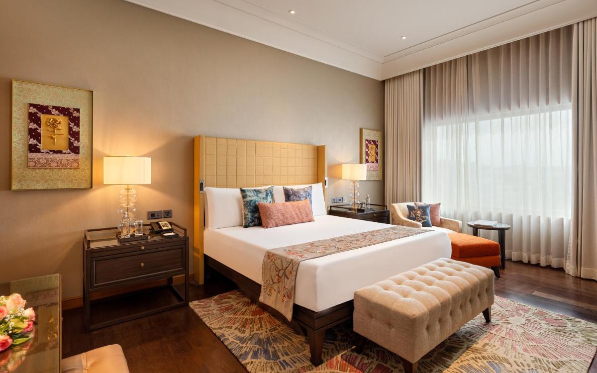 a bedroom with a large white bed and a window at The Leela Hyderabad Banjara Hills in Hyderabad