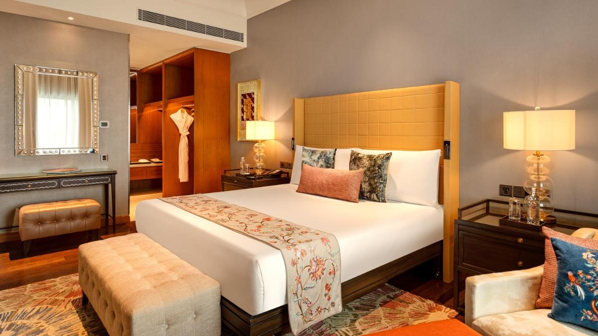 a bedroom with a large bed and a chair at The Leela Hyderabad Banjara Hills in Hyderabad