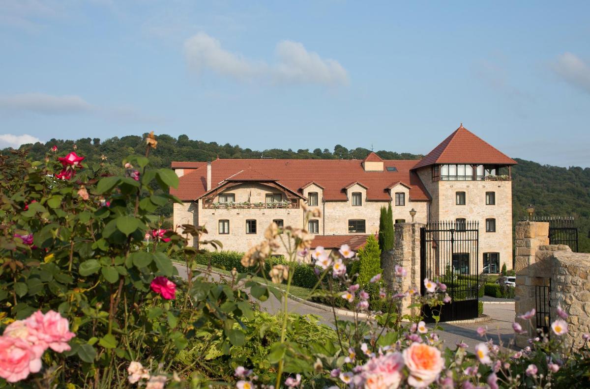 un grand bâtiment avec des fleurs devant lui dans l'établissement Domaine de la Klauss & Spa, Restaurant Gastronomique Le K, à Montenach