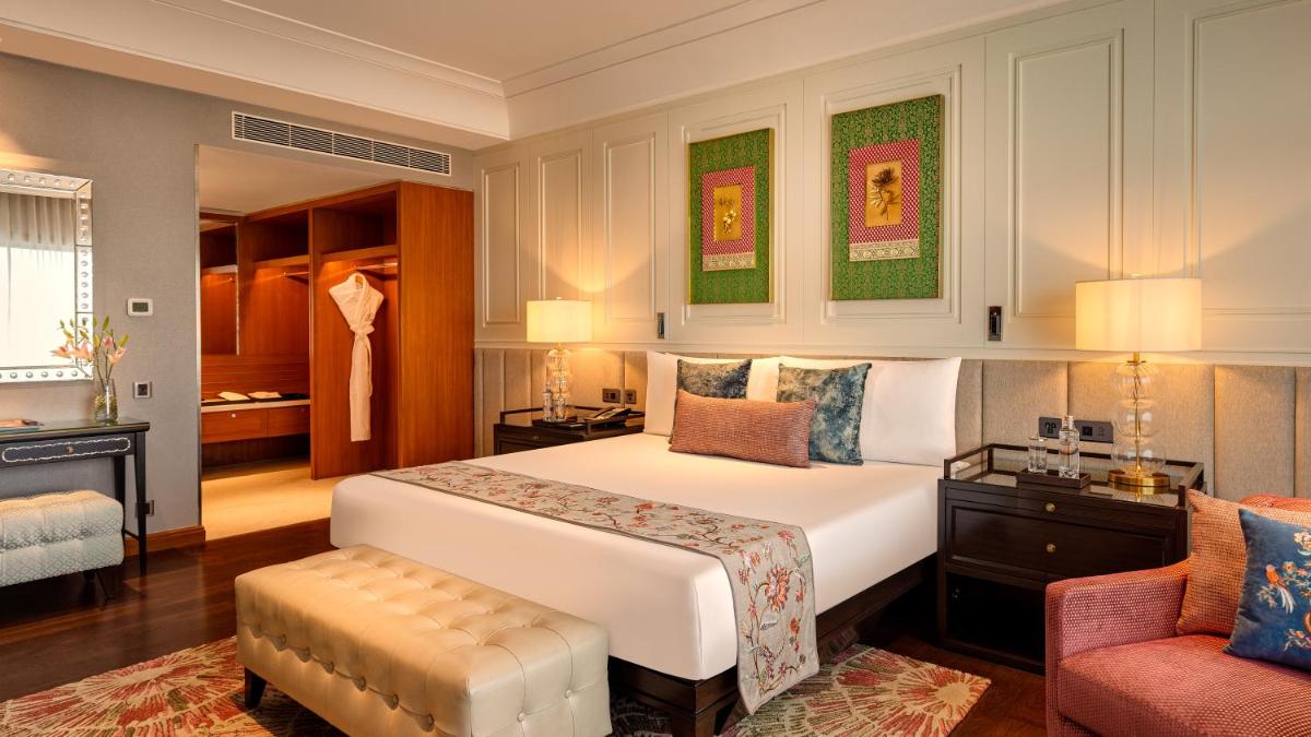 a bedroom with a large white bed and a chair at The Leela Hyderabad Banjara Hills in Hyderabad