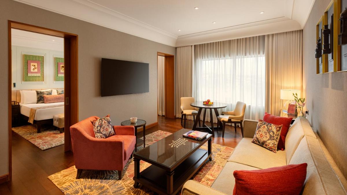 a living room with a couch and a room with a bed at The Leela Hyderabad Banjara Hills in Hyderabad