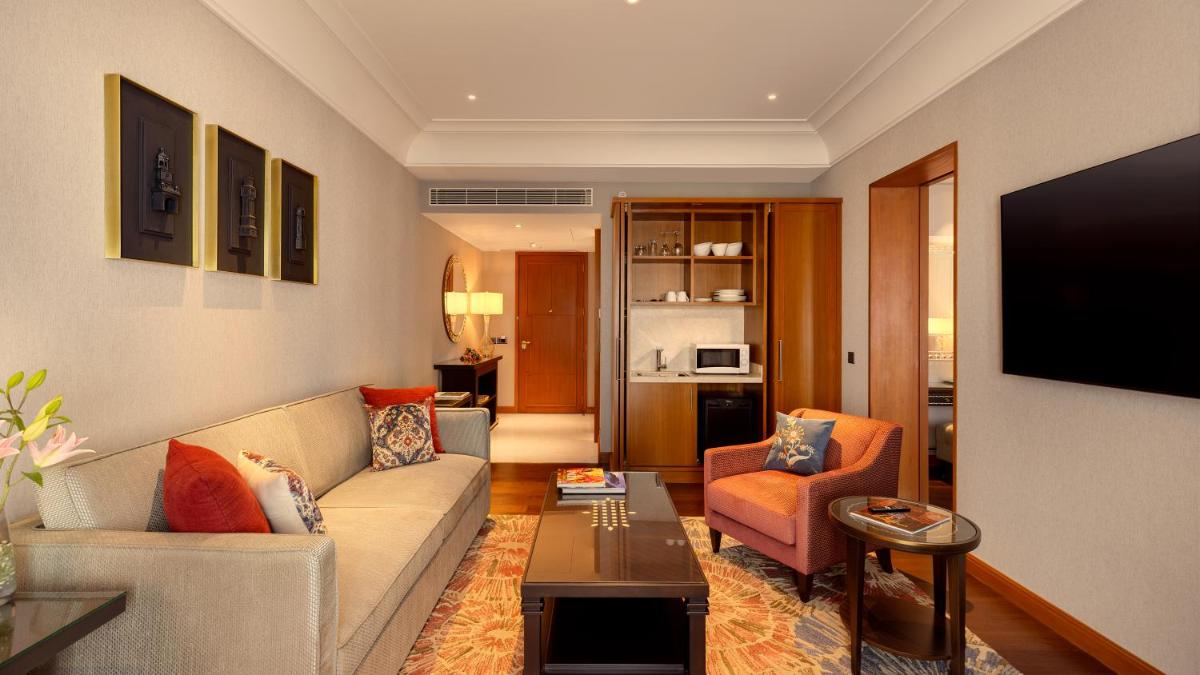 a living room with a couch and a tv at The Leela Hyderabad Banjara Hills in Hyderabad