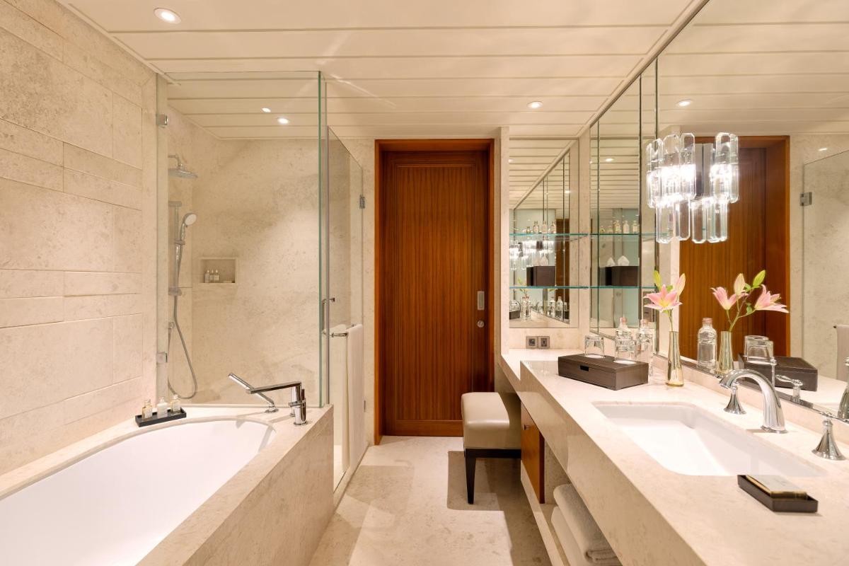 a bathroom with two sinks and a bath tub at The Leela Hyderabad Banjara Hills in Hyderabad