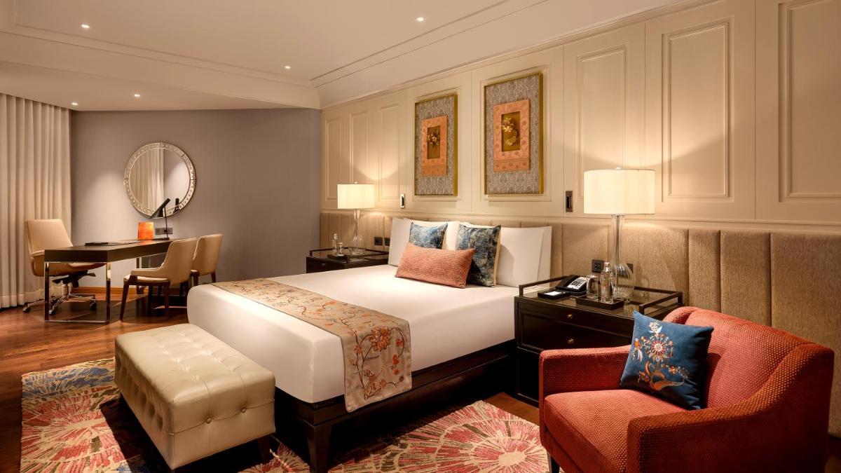 a hotel room with a bed and a table and chairs at The Leela Hyderabad Banjara Hills in Hyderabad