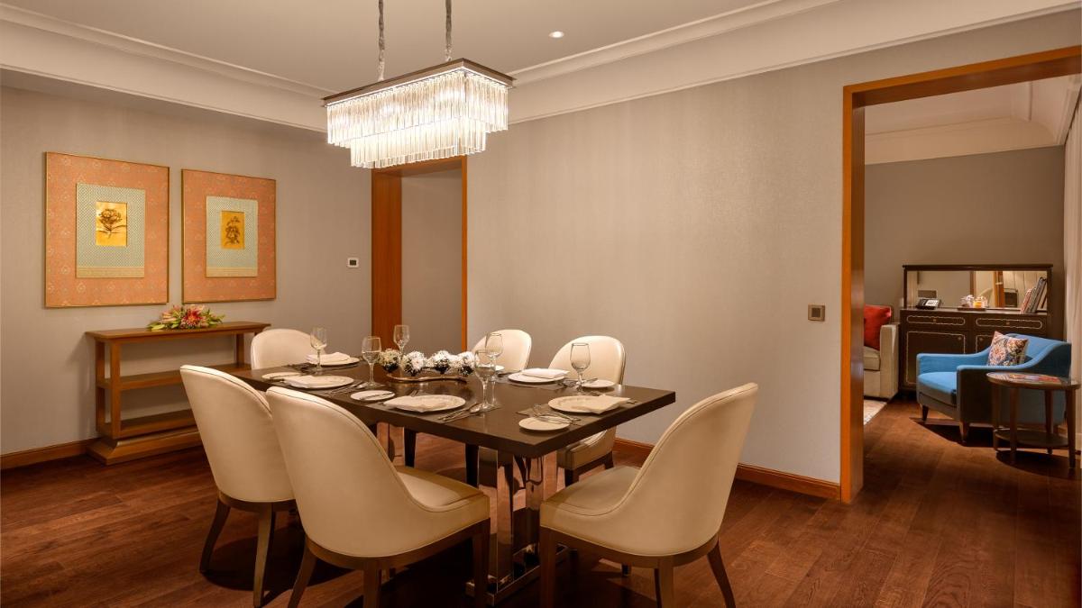 a dining room with a table and white chairs at The Leela Hyderabad Banjara Hills in Hyderabad