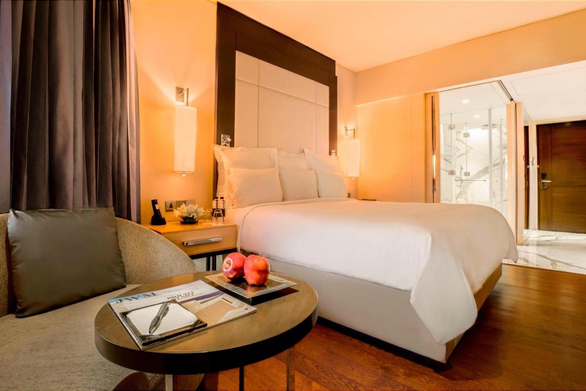 a hotel room with a large bed and a table at JW Marriott Mumbai Juhu in Mumbai