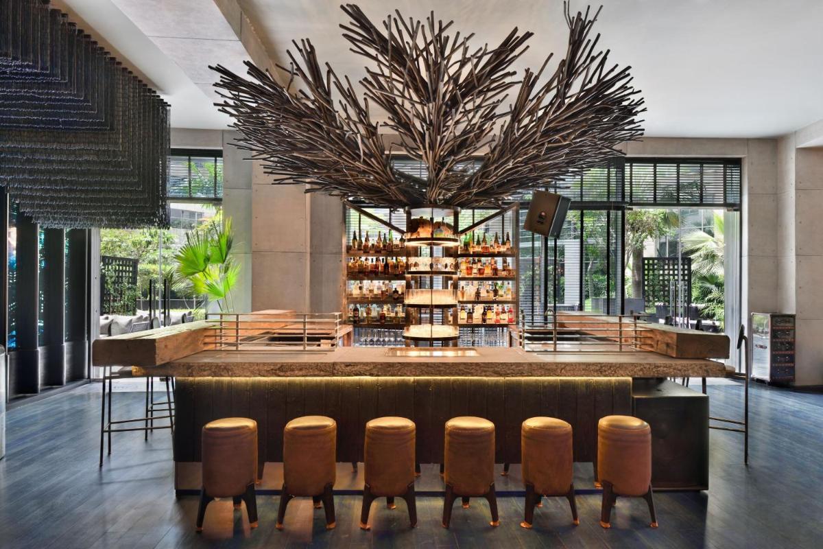 a restaurant with a bar with a bunch of chairs at JW Marriott Hotel New Delhi Aerocity in New Delhi a restaurant with a bar with a bunch of chairs at JW Marriott Hotel New Delhi Aerocity in New Delhi