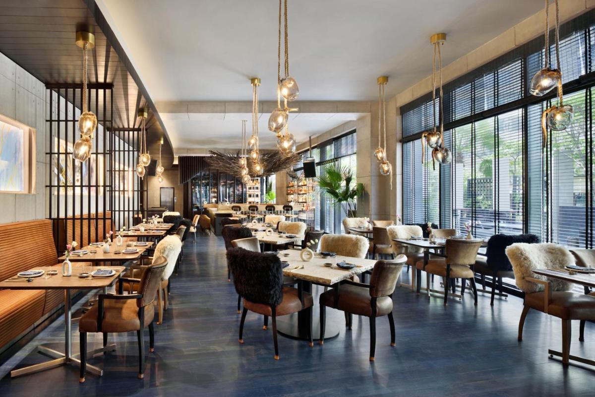 a restaurant with tables and chairs and large windows at JW Marriott Hotel New Delhi Aerocity in New Delhi a restaurant with tables and chairs and large windows at JW Marriott Hotel New Delhi Aerocity in New Delhi