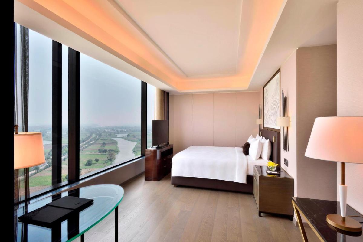 a hotel room with a bed and a glass table at JW Marriott Hotel Kolkata in Kolkata