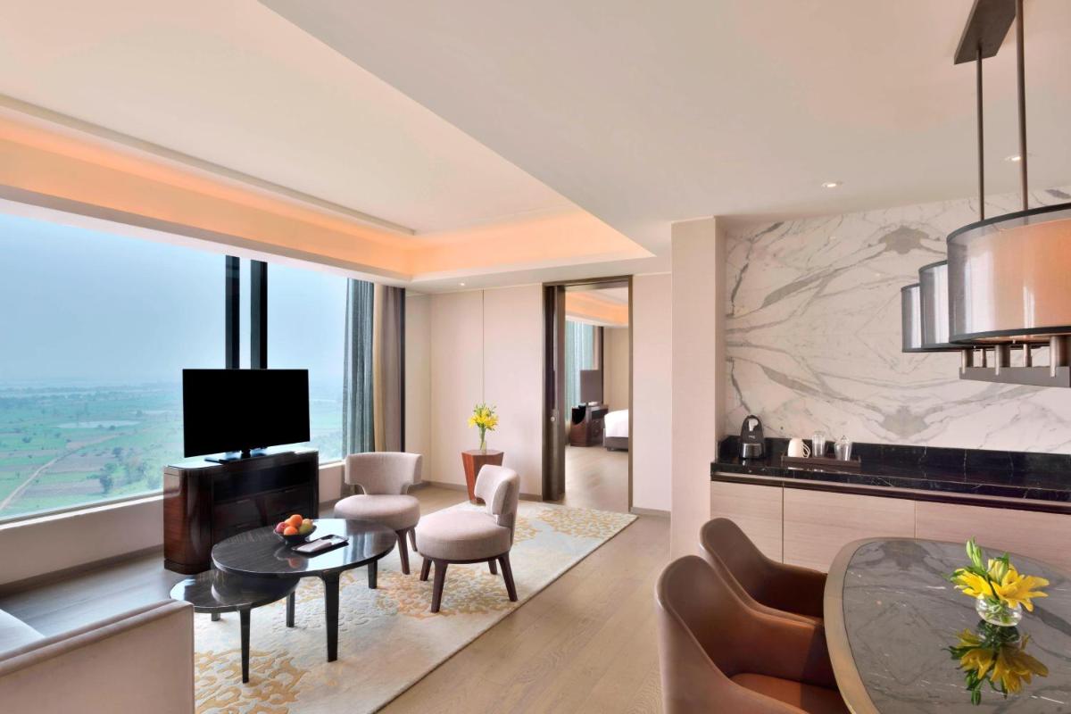 a living room with a table and chairs and a dining room at JW Marriott Hotel Kolkata in Kolkata