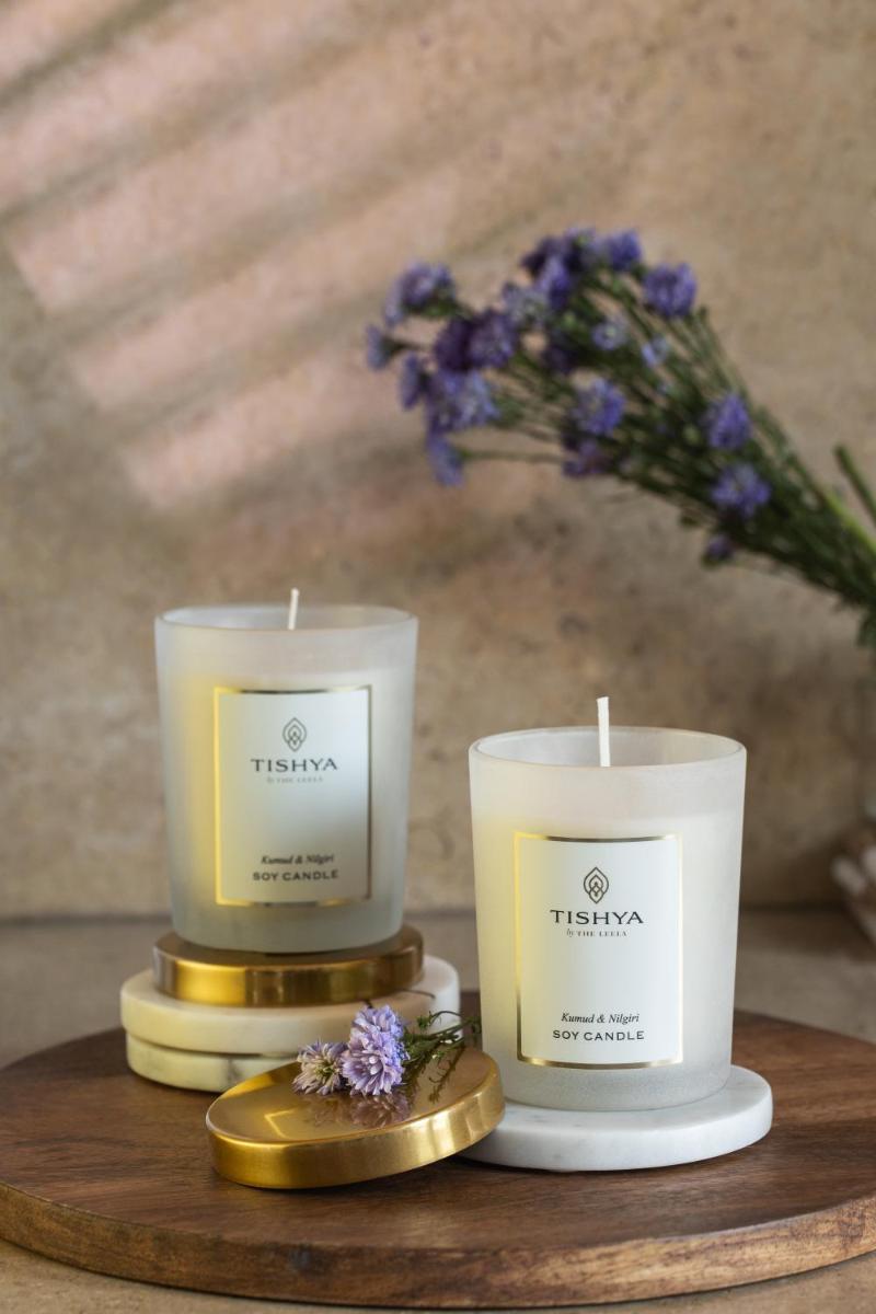 two candles sitting on a wooden table with flowers at The Leela Palace Chennai in Chennai two candles sitting on a wooden table with flowers at The Leela Palace Chennai in Chennai