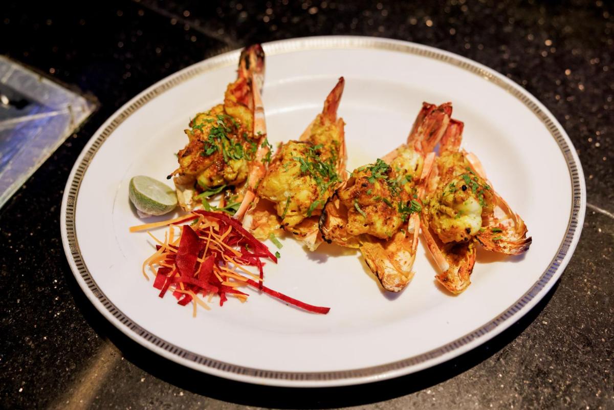 a white plate with food on a table at The Leela Palace Chennai in Chennai a white plate with food on a table at The Leela Palace Chennai in Chennai