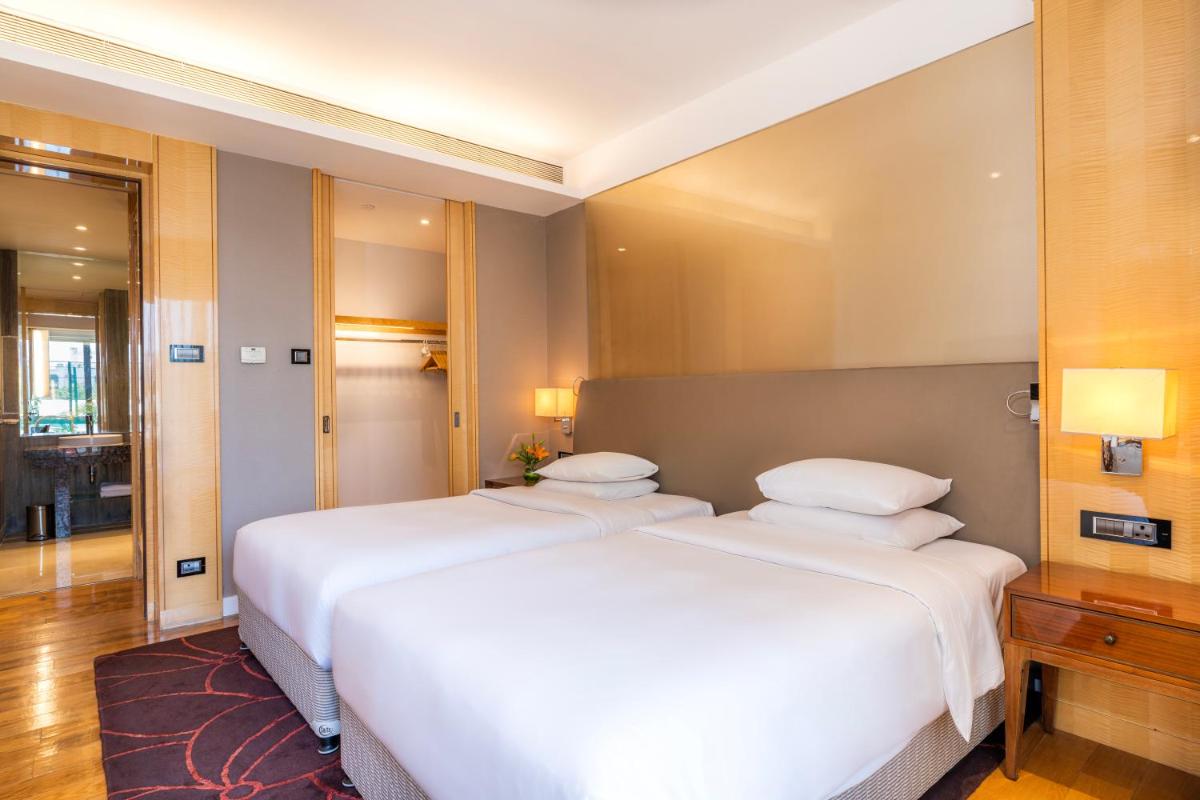 two beds in a hotel room with white sheets at Hyatt Regency Pune Hotel & Residences in Pune