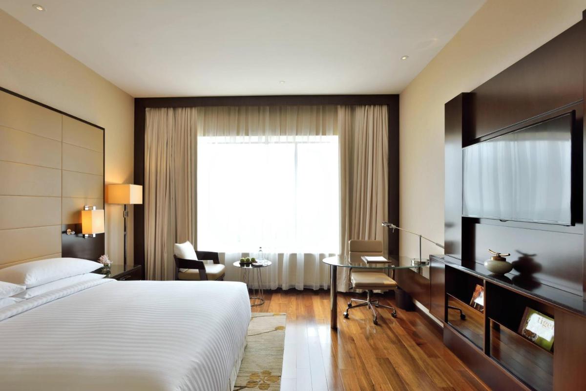 a bedroom with a bed and a desk and a window at Kochi Marriott Hotel in Cochin