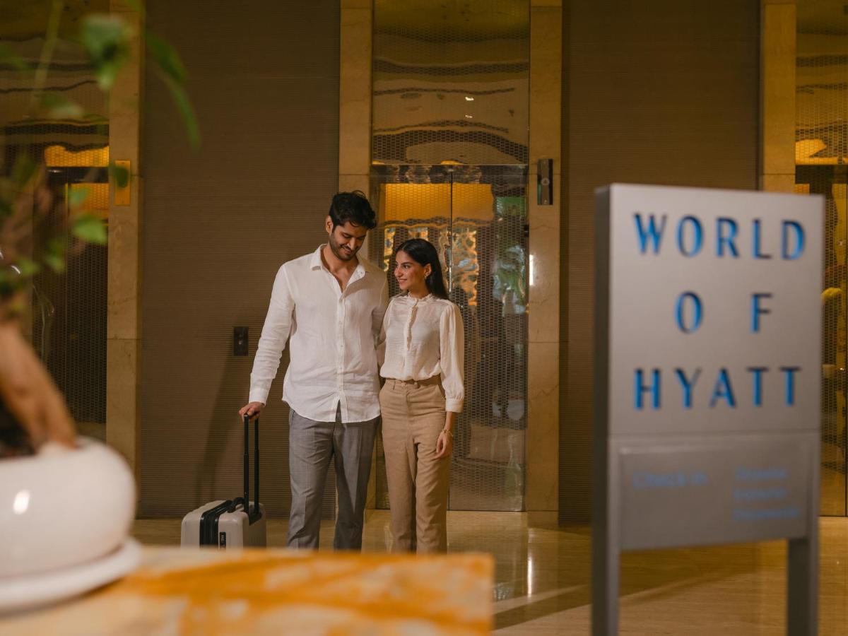 a man and woman standing in front of a world of hyatt sign at Hyatt Regency Pune Hotel & Residences in Pune