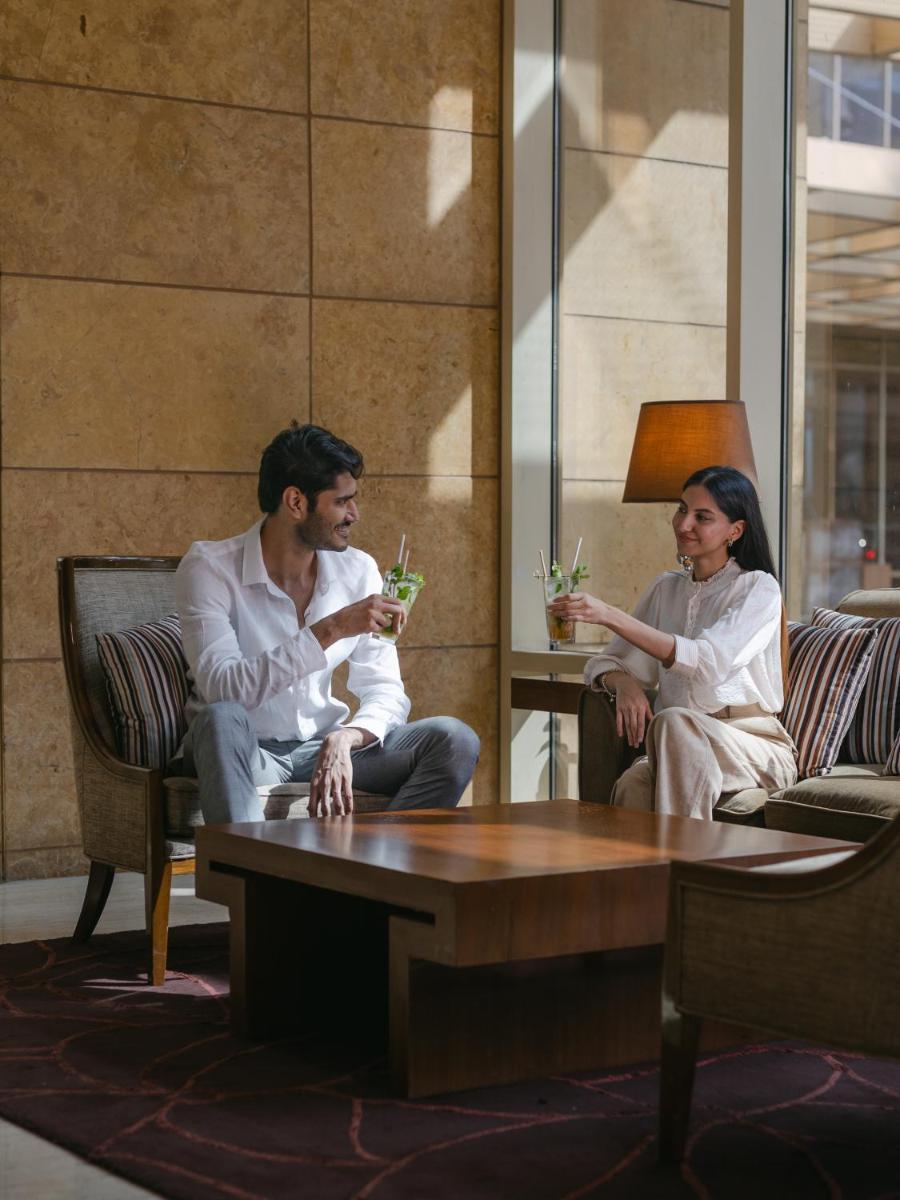 a man and woman sitting in chairs in a room at Hyatt Regency Pune Hotel & Residences in Pune