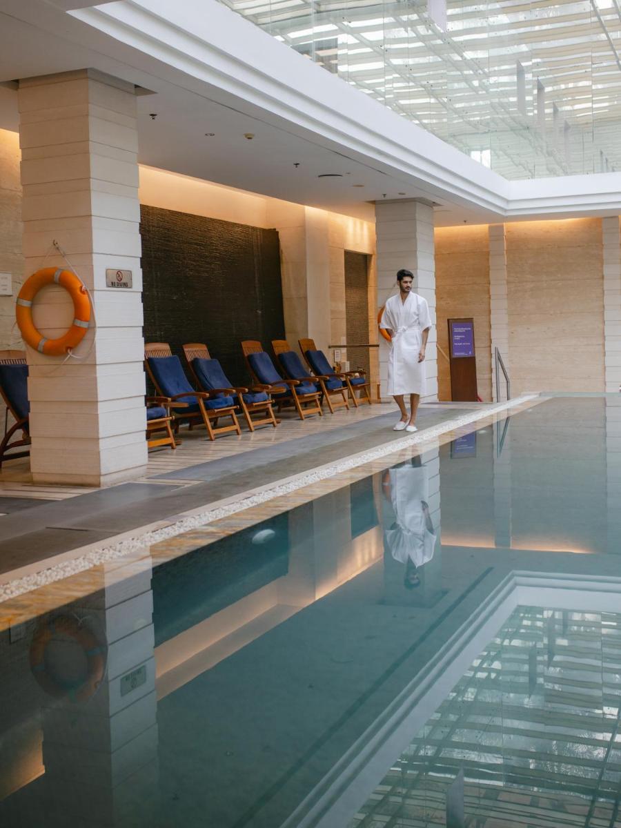 a woman is standing next to a swimming pool at Hyatt Regency Pune Hotel & Residences in Pune