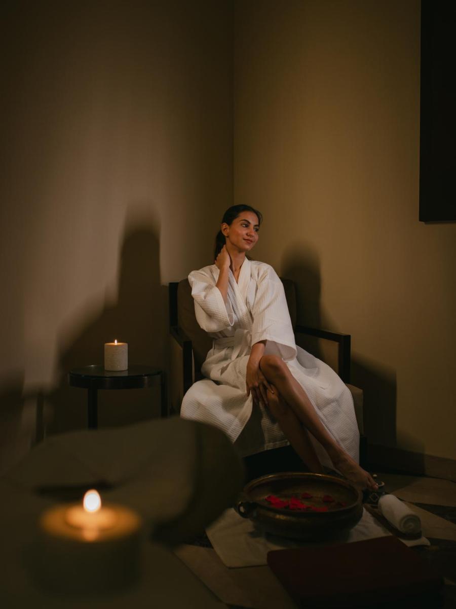 a woman in a robe sitting in a chair with a candle at Hyatt Regency Pune Hotel & Residences in Pune