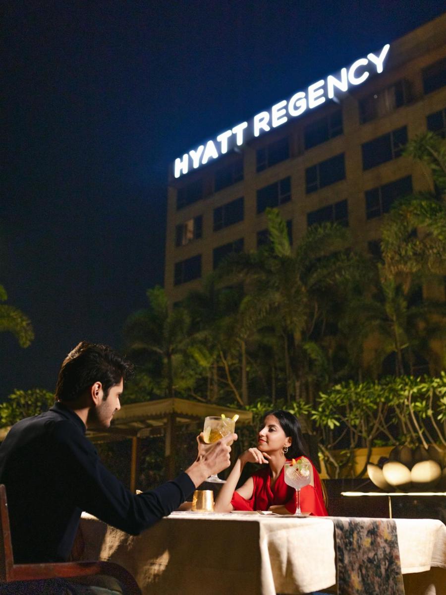 a man and woman sitting at a table with drinks at Hyatt Regency Pune Hotel & Residences in Pune