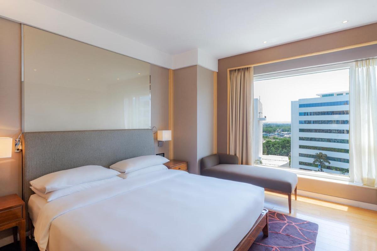 a bedroom with a large bed and a large window at Hyatt Regency Pune Hotel & Residences in Pune