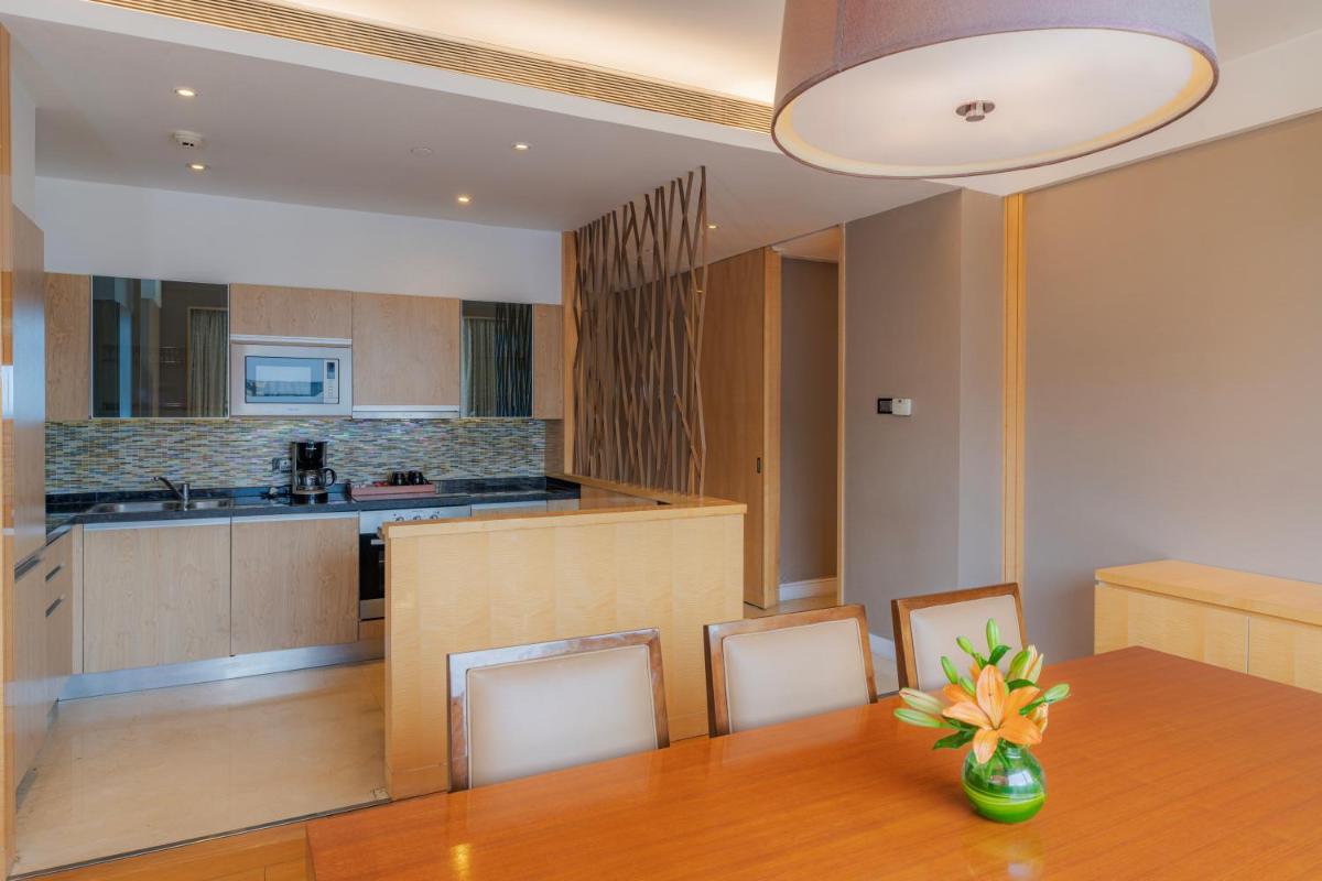 a kitchen with a wooden table and a dining room at Hyatt Regency Pune Hotel & Residences in Pune