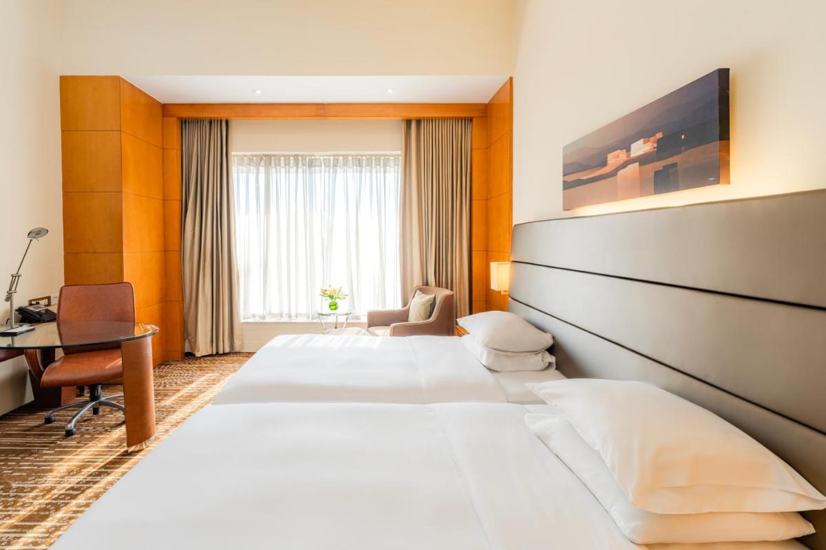 a hotel room with two beds and a desk at Hyatt Regency Pune Hotel & Residences in Pune