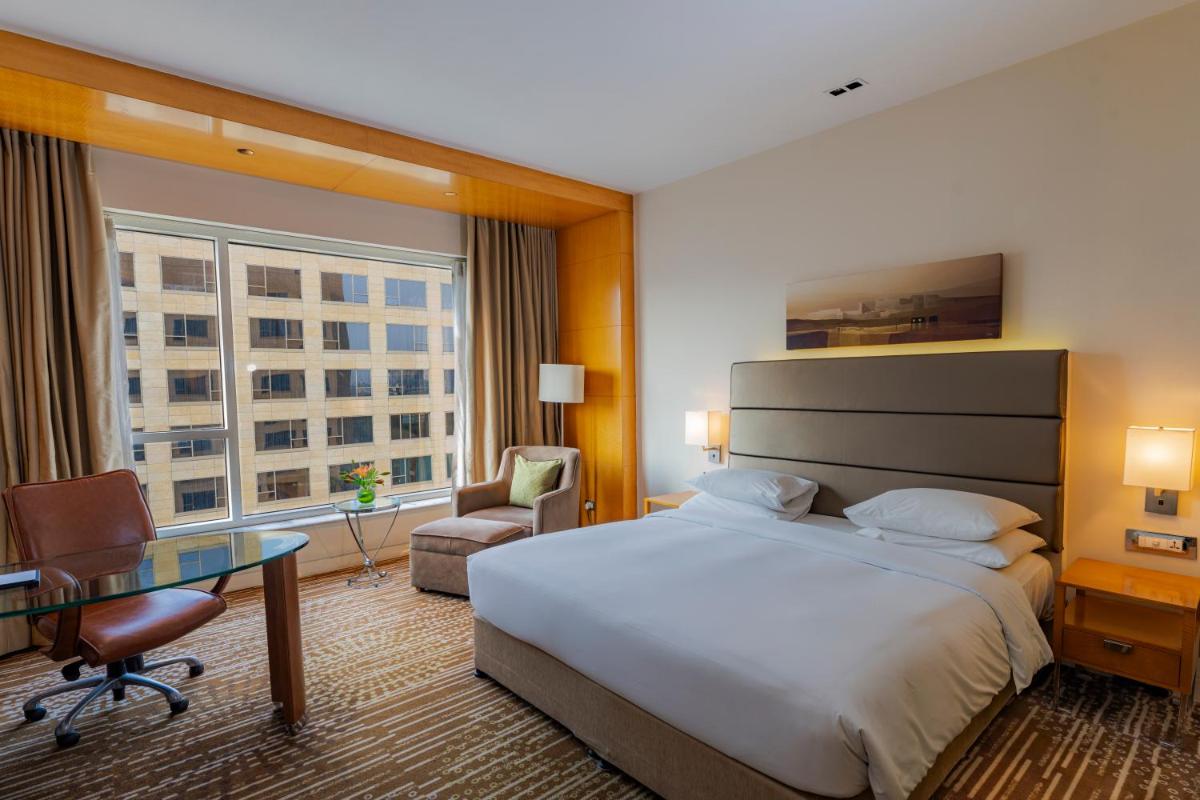 a hotel room with a large bed and a desk at Hyatt Regency Pune Hotel & Residences in Pune a hotel room with a large bed and a desk at Hyatt Regency Pune Hotel & Residences in Pune