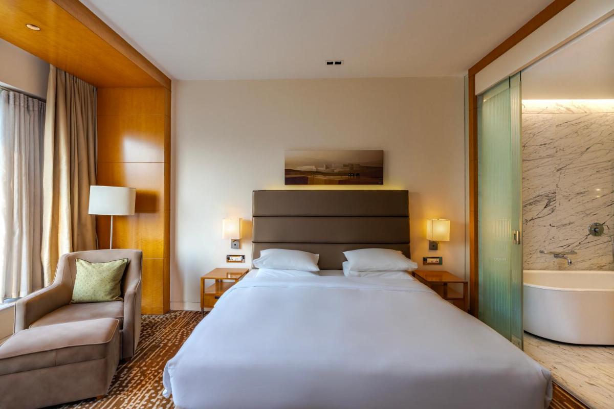a hotel room with a large bed and a chair at Hyatt Regency Pune Hotel & Residences in Pune