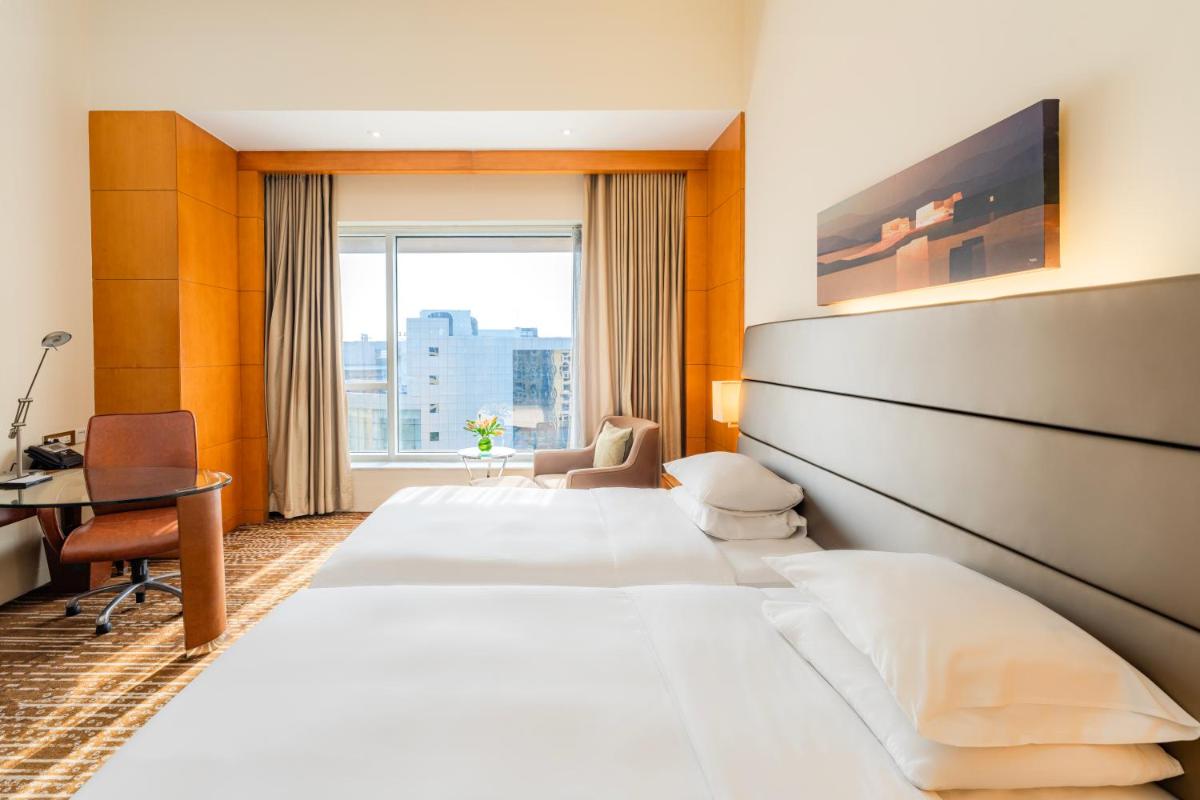 a hotel room with two beds and a desk at Hyatt Regency Pune Hotel & Residences in Pune